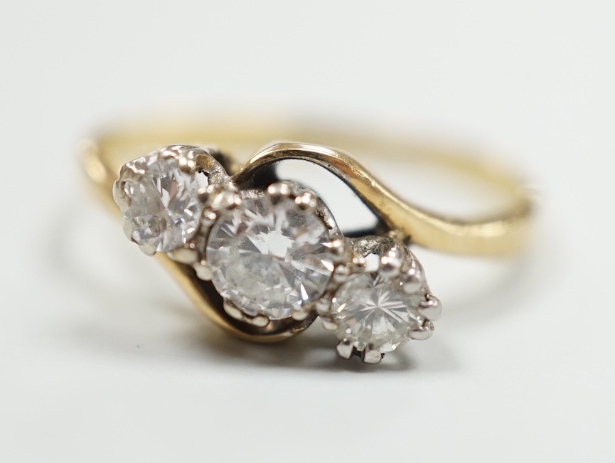 A yellow metal and three stone diamond set crossover ring, size K, gross weight 2.1 grams